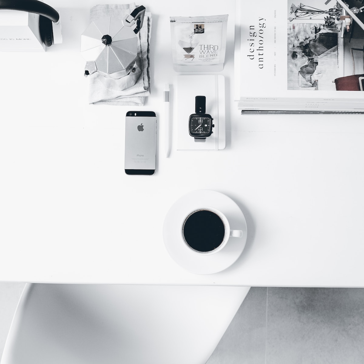 a white desk with a cup of coffee and a cell phone