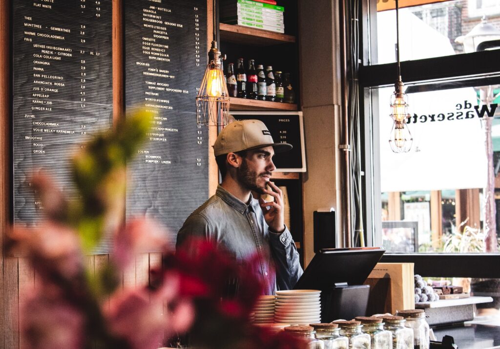 man wearing brown cap in across menu board