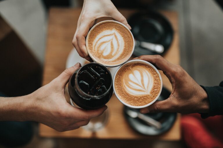 person holding cappuccino in black ceramic mug